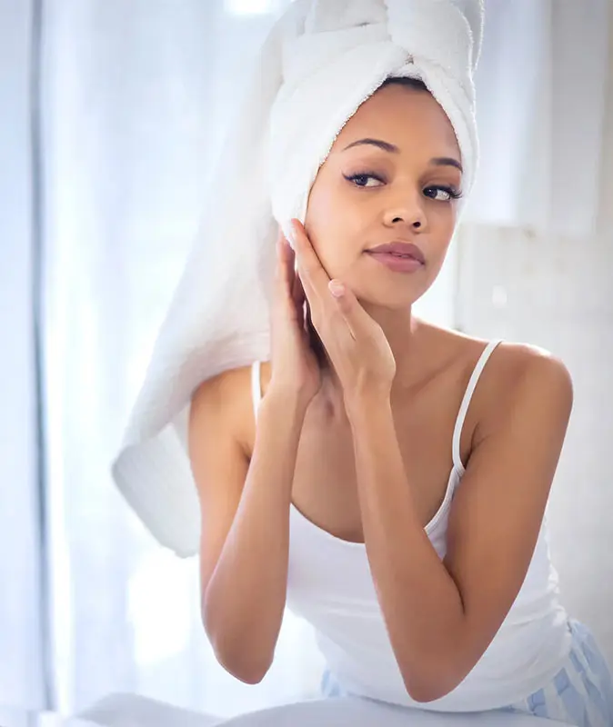 black woman looking at herself in the mirror skinvive